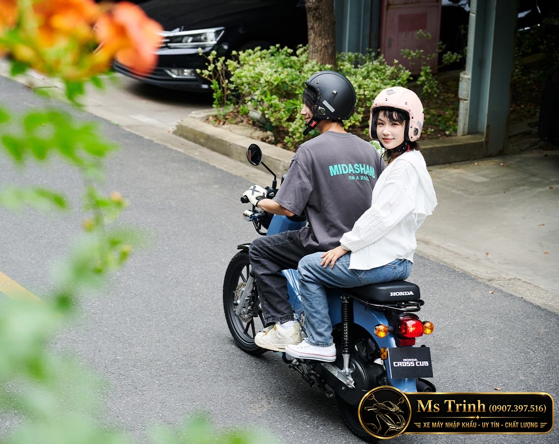 Honda Cross Cub 110 2026 chở hai người trên đường với thiết kế yên trước sau riêng biệt